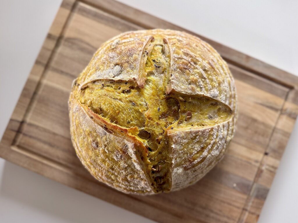 A round sourdough loaf with a deep brown, blistered crust