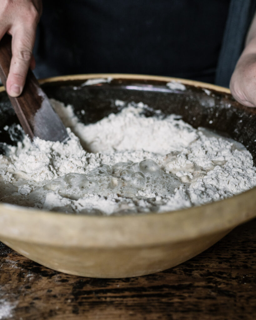 Sourdough starter being mixed into flour in a bowl